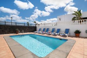 a swimming pool with chairs and a building at Villa Carolina in Tías