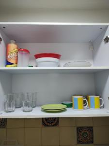 a kitchen shelf with cups and plates and glasses at Studio 7 - Hospital Italiano in Buenos Aires