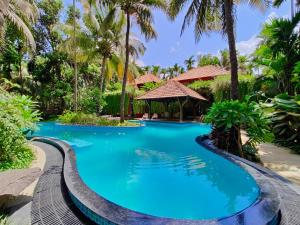 una piscina en un resort con palmeras en SaffronStays Kimaya, Alibaug, en Alibaug