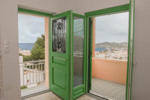 Una puerta verde en una habitación con 2 ventanas en Ano Siroa, en Ano Syros