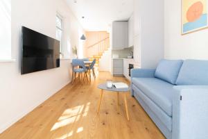 a living room with a blue couch and a table at Karklė Living Apartments, By Cohost in Karklė
