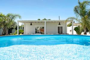 a large blue swimming pool in front of a house at La Casita de la Florida in Conil de la Frontera