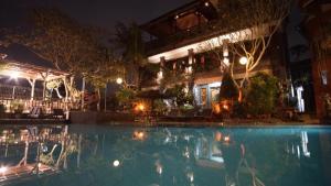 a swimming pool in front of a building at night at Okawati Boutique Bungalows in Ubud