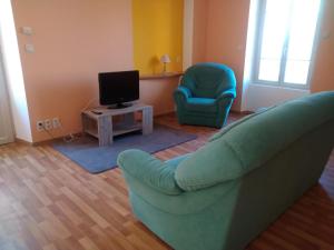 a living room with a couch and a chair and a television at Les Chambres de Marvejols in Marvejols