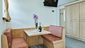 a table with a bottle of wine and a vase with purple flowers at Hotel 2000 in Livigno