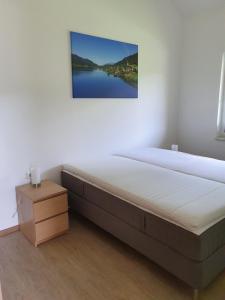 uma cama num quarto com uma fotografia na parede em Ferienhäuser Seetraum em Weissensee