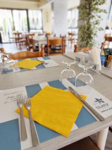 ガビッチェ・マーレにあるBlu Star Hotelの黄色のナプキンとフォークとナイフを入れたテーブル
