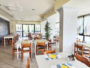 un restaurante con mesas y sillas blancas y ventanas en Blu Star Hotel, en Gabicce Mare