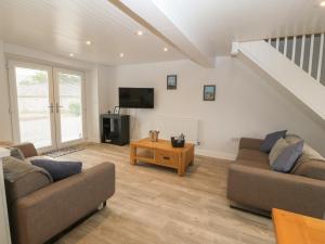 a living room with two couches and a tv at Bryn Eglwys Bach in Llanfairpwllgwyngyll