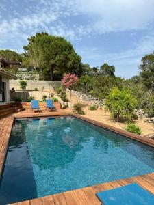 een zwembad met twee blauwe stoelen op een houten terras bij Villa Monte e Mare, piscine chauffée, climatisée à 5 mn de la plage de santa giulia in Porto-Vecchio