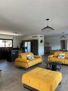 een woonkamer met gele banken en een keuken bij Villa Monte e Mare, piscine chauffée, climatisée à 5 mn de la plage de santa giulia in Porto-Vecchio