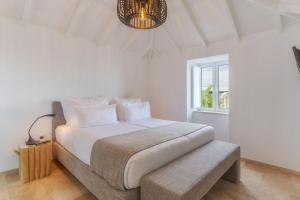 a bedroom with a large white bed with a bench at Escarpa - The Madeira Hideaway in Ponta do Sol