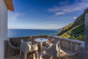 a table and chairs on a balcony overlooking the ocean at Escarpa - The Madeira Hideaway in Ponta do Sol