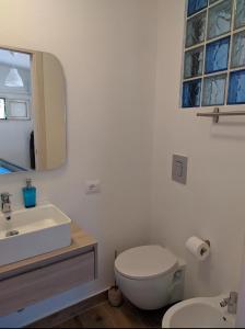 bagno con lavandino, servizi igienici e specchio di Cottage con veranda attrezzata giardino,vista mare a Carloforte