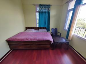 a bedroom with a bed with a purple comforter and two windows at Shimla Hills Apartments 2BHK in Shimla