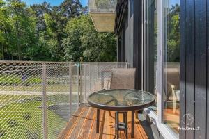 a glass table on a balcony with a fence at White Forest in Juodkrantė