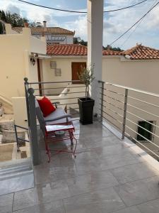 una silla sentada en un balcón con una casa en Up the stairs renovated apartment with sea view, en Poros 3 fotos más