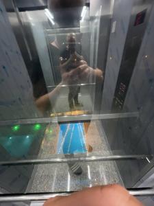 a man taking a picture in a glass elevator at Hotel Estonia Two in Kobuleti