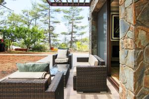d'une terrasse couverte avec des tables et des chaises en osier. dans l'établissement Phaedrus Living: Forest View Luxury Villa Chantara, à Phini