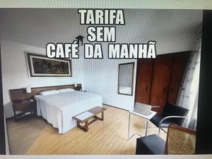 a bedroom with a white bed and a table at Hotel Germânia in Joinville