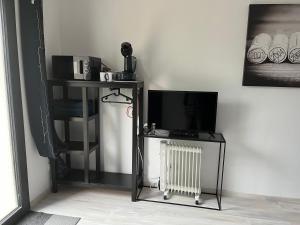 un salon avec une télévision et un radiateur dans l'établissement Chambre double indépendante HARMONIE au sein du domaine PASSELOUP, à Liergues
