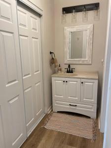 Baño blanco con lavabo y espejo en Sea Shanty - Steps from the beach en Jekyll Island