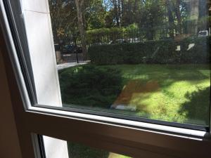 a window with a view of a yard at Trés Beau Studio (face bois), 10mn de l'Etoile in Neuilly-sur-Seine