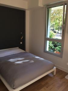 een slaapkamer met een bed en een raam bij Trés Beau Studio (face bois), 10mn de l'Etoile in Neuilly-sur-Seine
