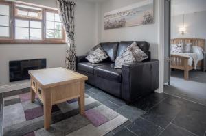 a living room with a black leather couch and a table at Lilac Cottage - 1 Bedroom Cottage - Amroth in Amroth +26 photos