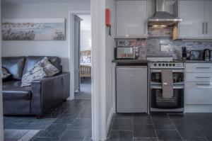 a kitchen with a stove and a couch at Lilac Cottage - 1 Bedroom Cottage - Amroth in Amroth