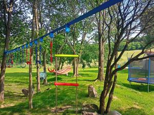 plac zabaw z kolorowymi huśtawkami w parku w obiekcie Cicha Dolina w Wydminach