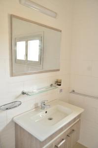 a white bathroom with a sink and a mirror at Ranch Tanit Djerba in Midoun