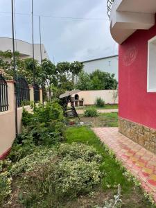 a yard with a red building and an umbrella at Vila Nadia in Eforie Nord