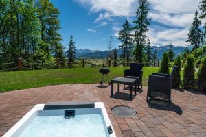 a hot tub with a table and chairs on a patio at Peak Glamp in Zakopane