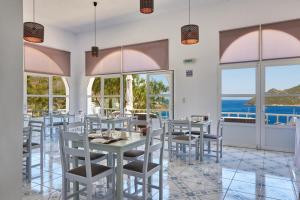 a dining room with tables and chairs and windows at HOTEL ATHINA in Grikos