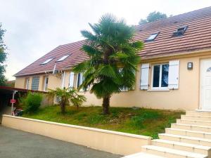 a palm tree in front of a house at Villa de 4 chambres avec piscine privee sauna et jardin clos a Villemeux sur Eure in Villemeux-sur-Eure