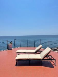 2 sedie a sdraio e un tavolo su una terrazza con vista sull'oceano di Salento Palace Bed & Breakfast a Gallipoli