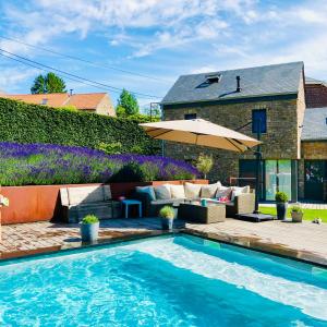 WanzeにあるJuste à Côté, Maison de caractère avec piscineのスイミングプールと傘付きの家