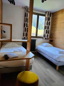 a room with two beds and a table and a window at Hôtel le Christiania in Arêches-Beaufort