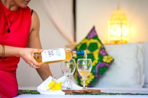 a woman pouring wine into a wine glass at Daima Villas in Jambiani