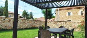eine Terrasse mit einem Tisch, Stühlen und einer Steinmauer in der Unterkunft Casa del Medio in Fuentecantos