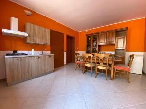 uma cozinha com paredes cor de laranja e uma mesa e cadeiras em Sole al Sud em Corigliano dʼOtranto