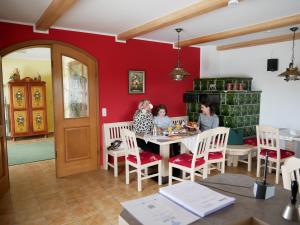 trzy kobiety siedzące przy stole w pokoju w obiekcie Pension Ambros w mieście Büchlberg