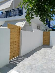 uma cerca branca e portas de madeira em frente a um edifício em Olga Studios Apartment em Faliraki
