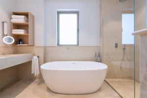 a white bath tub sitting inside of a bathroom at The Phoenicia Malta in Valletta