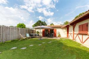 a backyard with a wooden fence and a yard with a patio at Maison Esprit Des Lois in La Brede