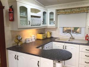 a kitchen with white cabinets and a black counter top at Beautiful 2-Bed holiday home nr Kynance cove in Helston