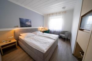 a bedroom with a bed and a desk and a television at Mühlenkamp Hotel & Gastronomie in Oelde