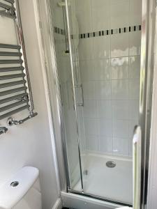 ein weißes Bad mit einer Dusche und einem WC in der Unterkunft Courtyard Cottage in Knaresborough