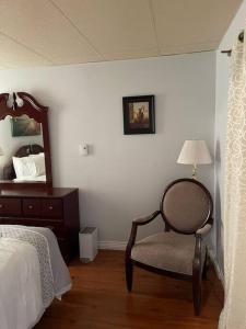 um quarto com uma cama, uma cadeira e um espelho em My Cozy Apartment Cottage em Grande-Digue